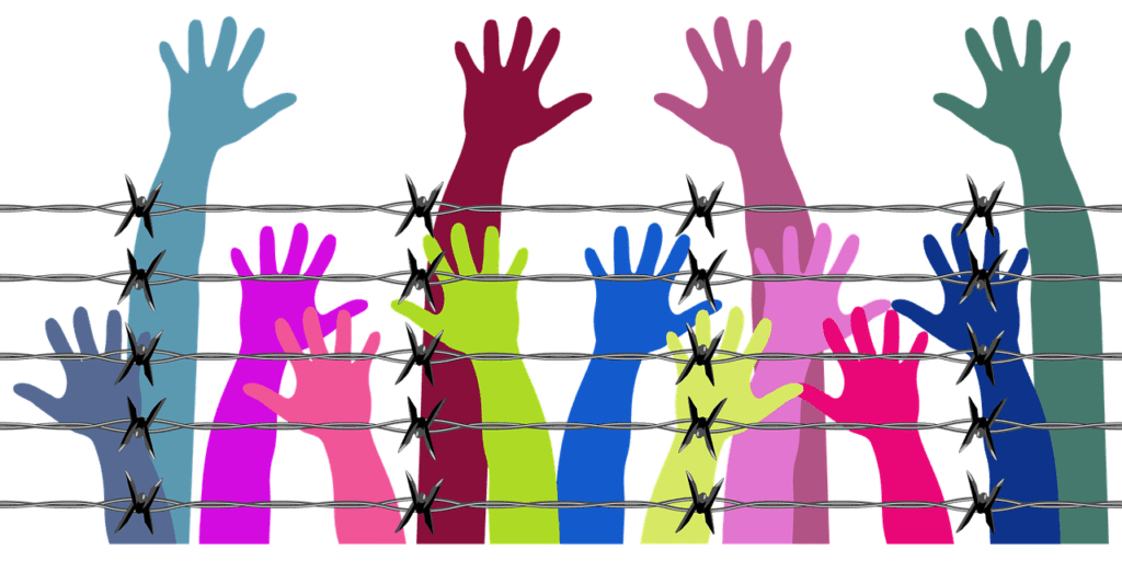 Colourful hands reaching behind barbed wire