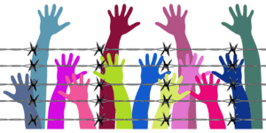 Colourful hands reaching behind barbed wire