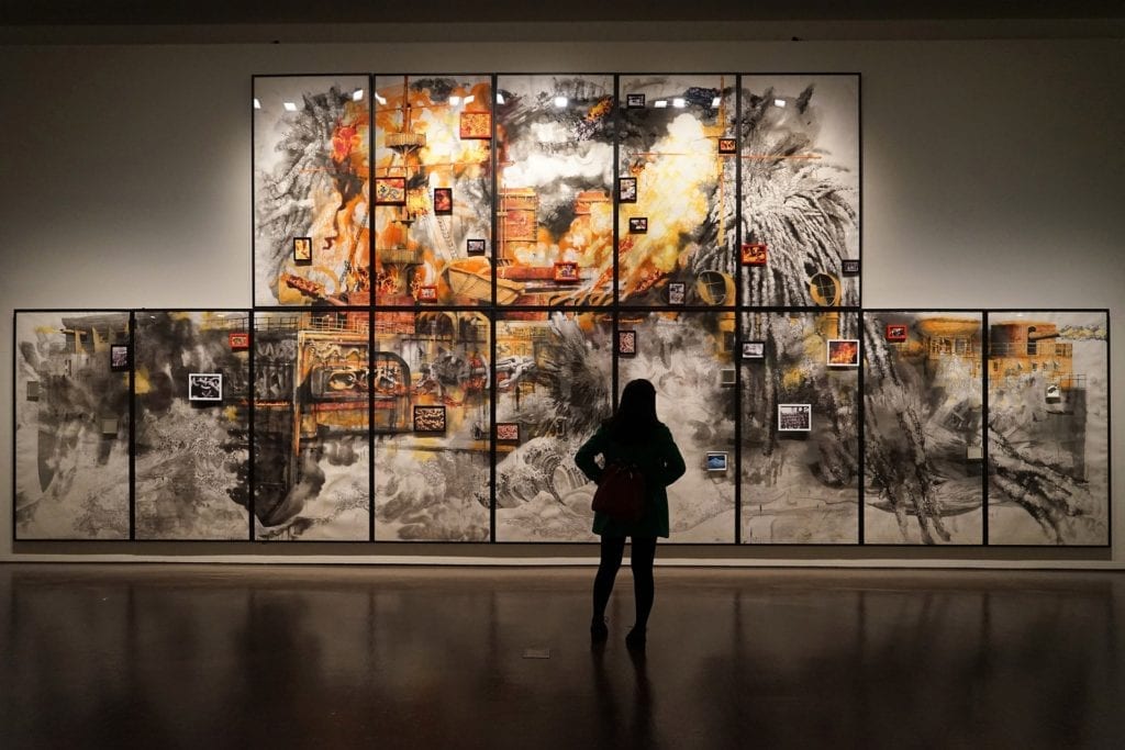 person standing in front of paintings in a gallery