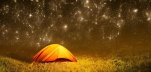 Yellow tent under a night sky with thousands of stars